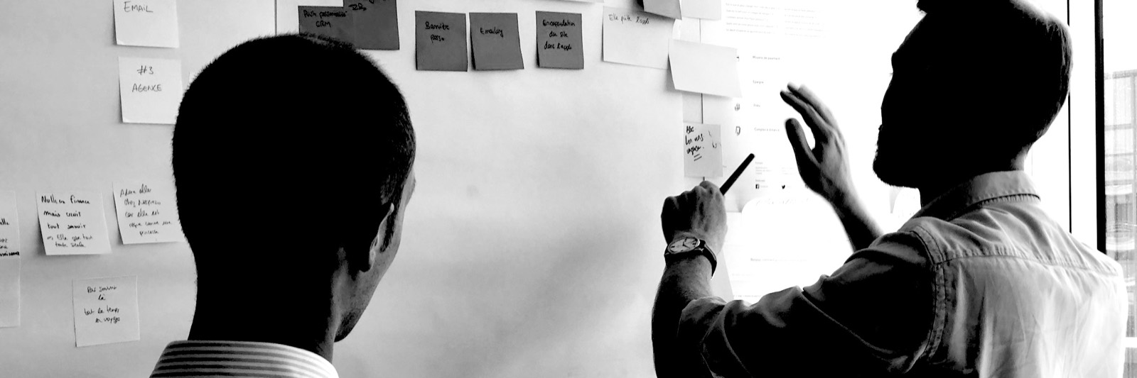 Two people working at a wall of sticky notes